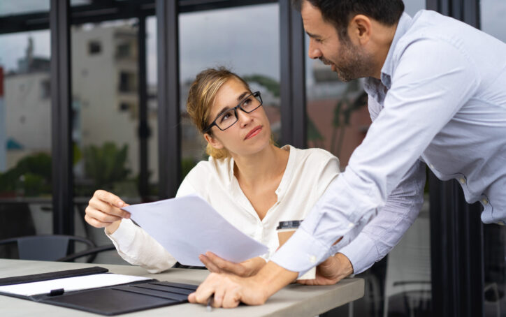 Businessman asking expert to check document. Male and female colleagues discussing reports at outdoor cafe. Expertise concept