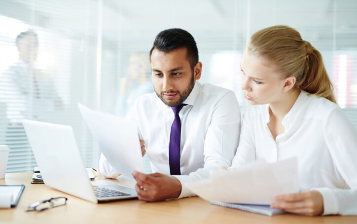 Young businessman showing paper to his colleague while working in office