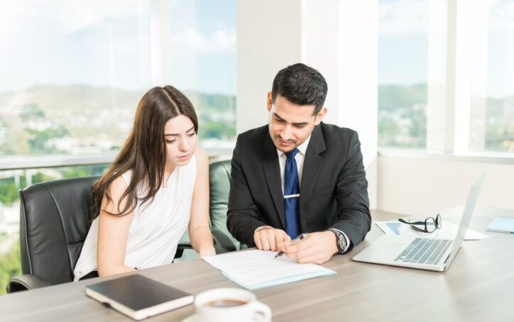 Young adviser explaining legal document to client in his office